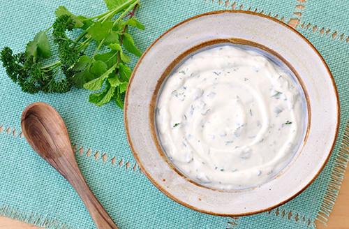 bowl of yogurt with herbs scattered throughout